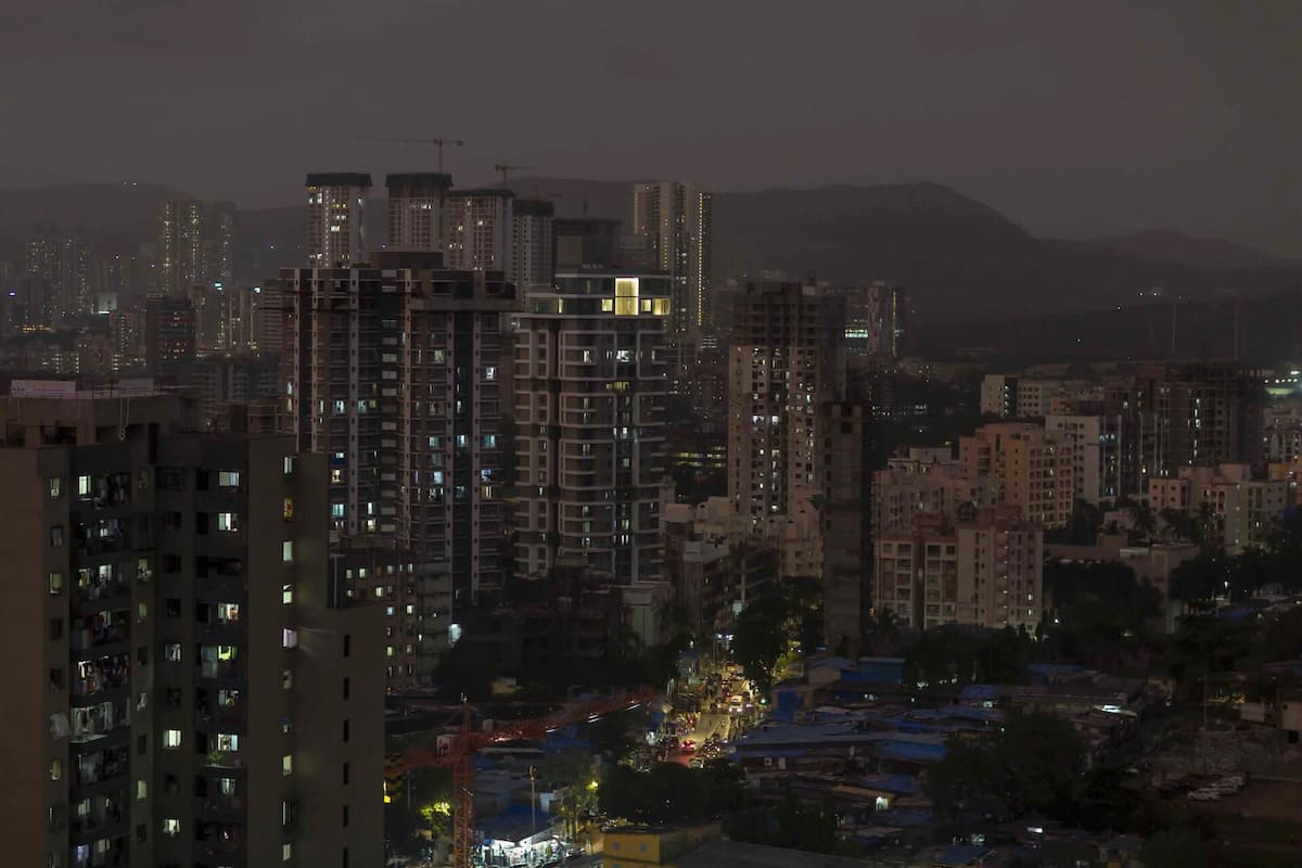 A photo of the Mumbai city skyline at night, with lighted windows in skyscrapers and mountains in the distance.