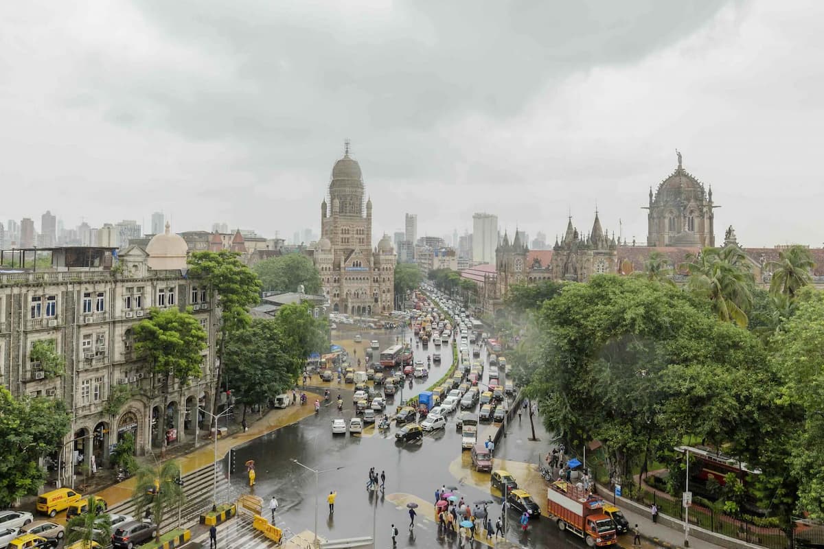 A photo of the Mumbai skyline and a busy intersection by a historic railway station, formerly known as Victoria Terminus.