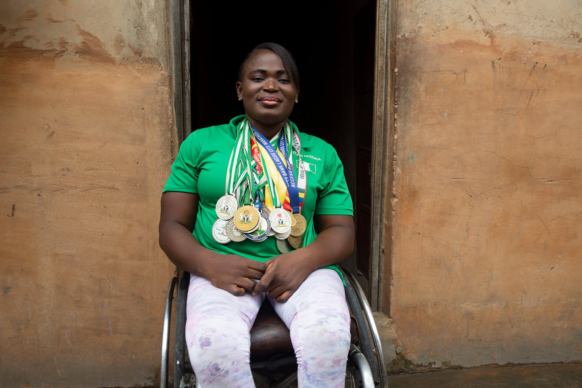 Olajumoke wears all her medals and smiles at the camera.