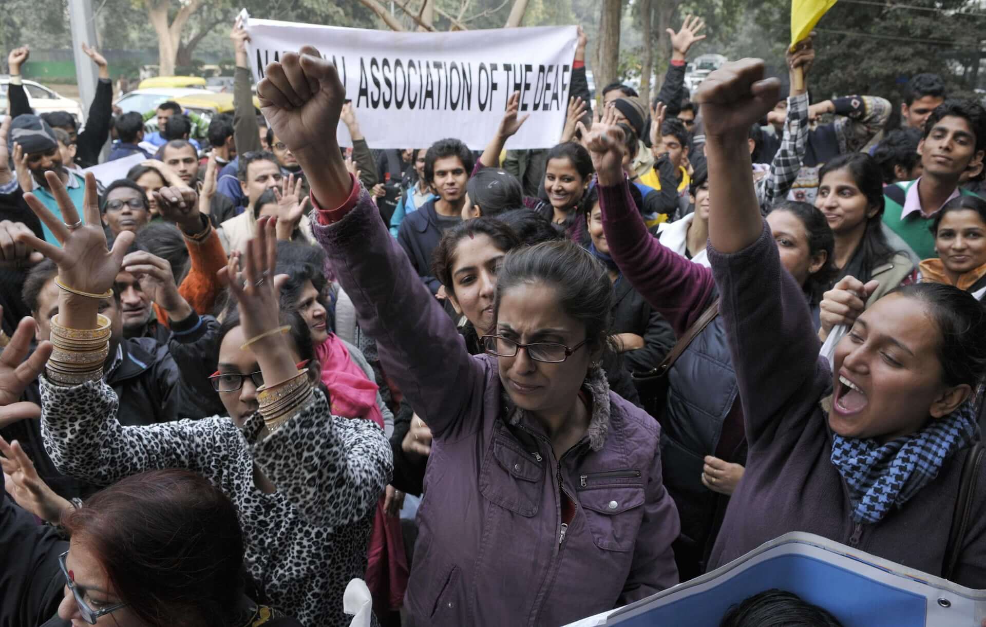 Various groups of disabled rights protesters raise their fists in the air protesting against the government for not introducing a Disability Rights Bill in December 2013 in New Delhi, India. One group carries a banner for the National Association of the Deaf. 
