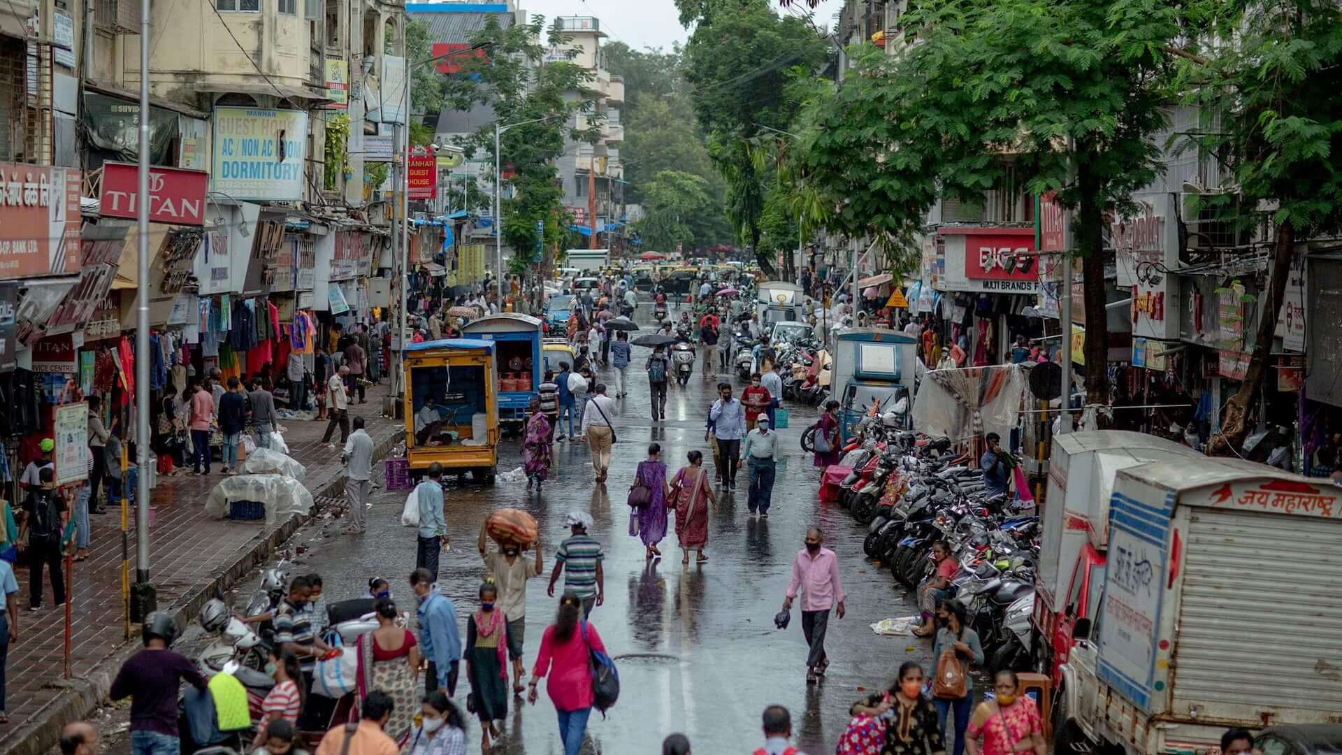A street in Mumbai is crowded with pedestrians, delivery trucks and scooters.