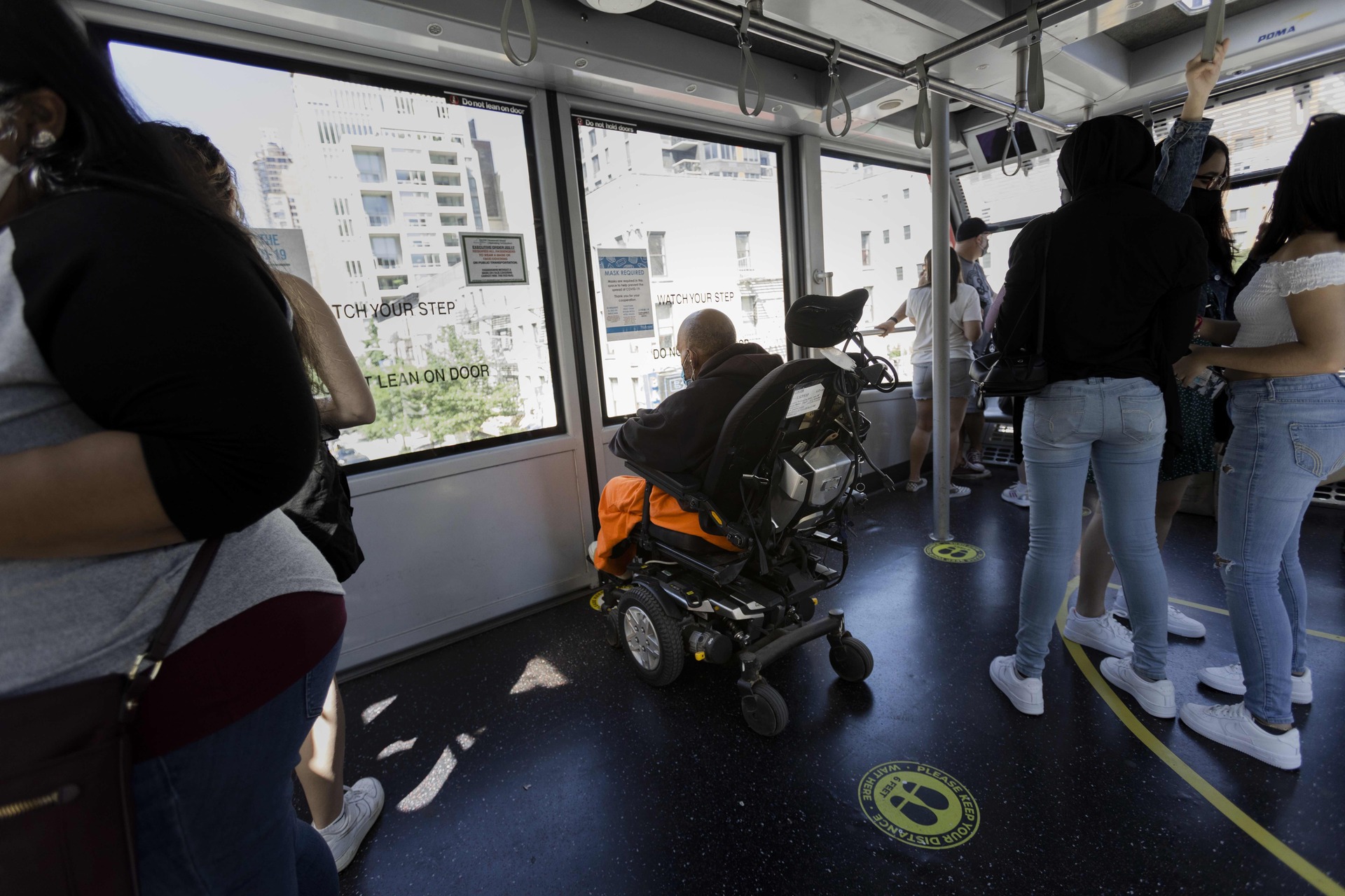 A man in a power wheelchair looks out the window, on the Roosevelt Island Tramway.